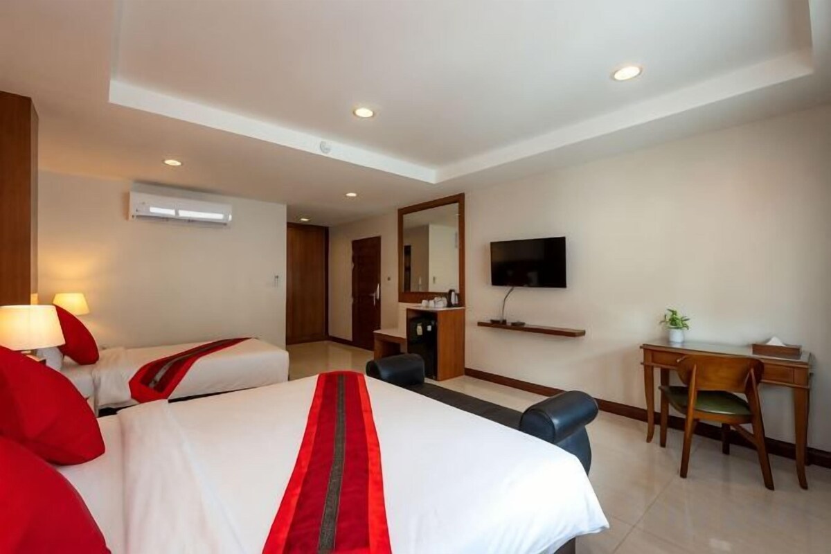 Habitación de hotel con dos camas, un escritorio, una silla, un televisor y un espejo.