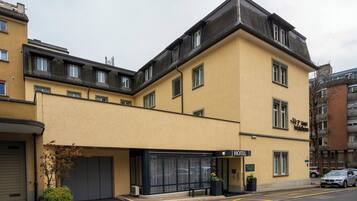 Un hôtel à la façade jaune, doté d’une entrée couverte et d’une enseigne indiquant qu’il s’agit d’un hôtel.
