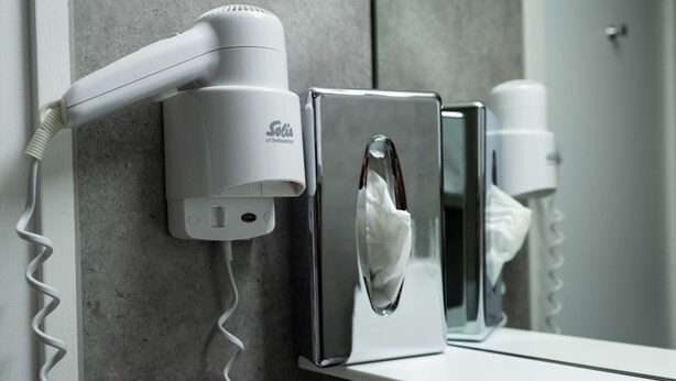 Secador de pelo y dispensador de pañuelos de papel fijados a una pared en un baño.