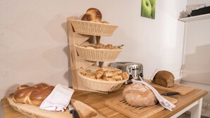 A wooden table with bread, a toaster, and a cutting board. - Hotel Waldhorn (Bern)