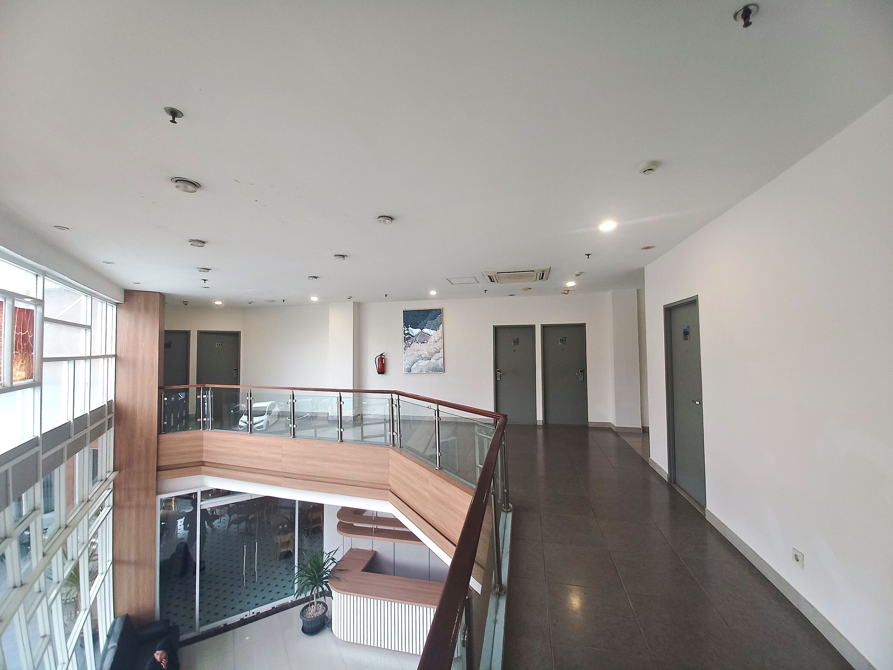 Un vestíbulo amplio con barandilla de vidrio, una mesa de recepción y vistas al nivel inferior.