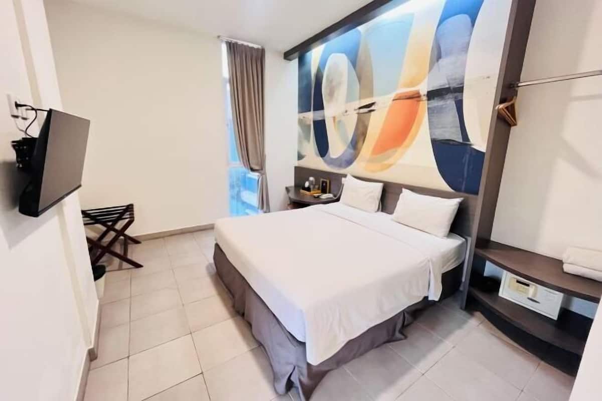 Habitación de hotel con cama, televisión, escritorio y un cuadro abstracto grande en la pared.