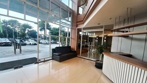 A spacious lobby with a reception desk, a black sofa, and large windows offering a view of parked cars outside. - Hotel 88 Kedoya Jakarta (Jakarta)
