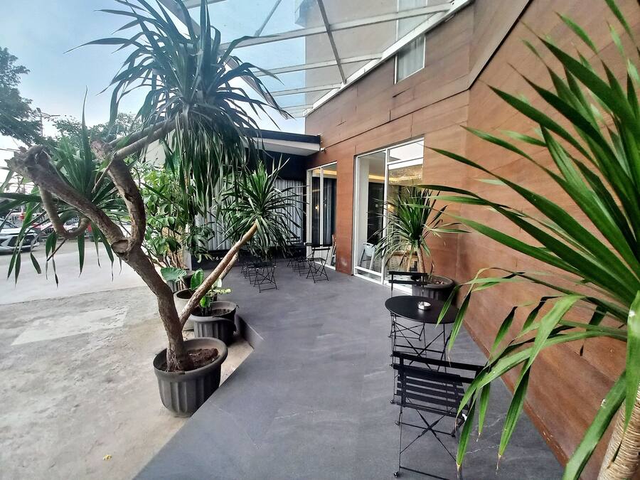 An outdoor seating area with potted plants and a modern building facade.