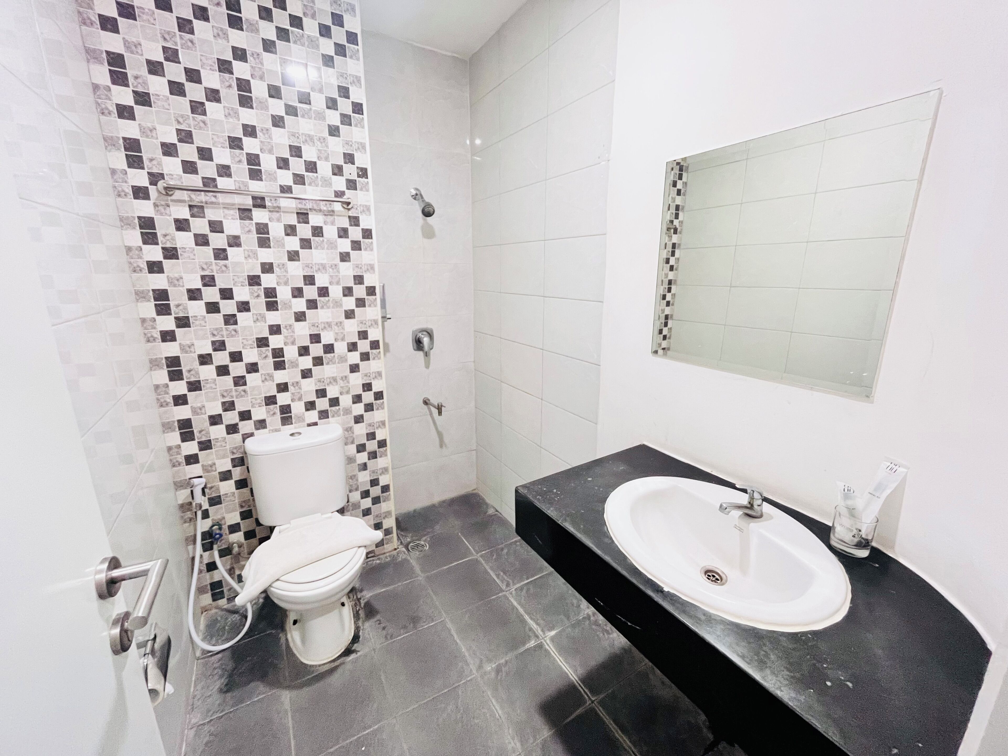 Un baño con ducha azulejada, inodoro, lavabo y espejo.