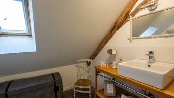 A bathroom with a large window, a white sink, a wooden chair, and a mirror.