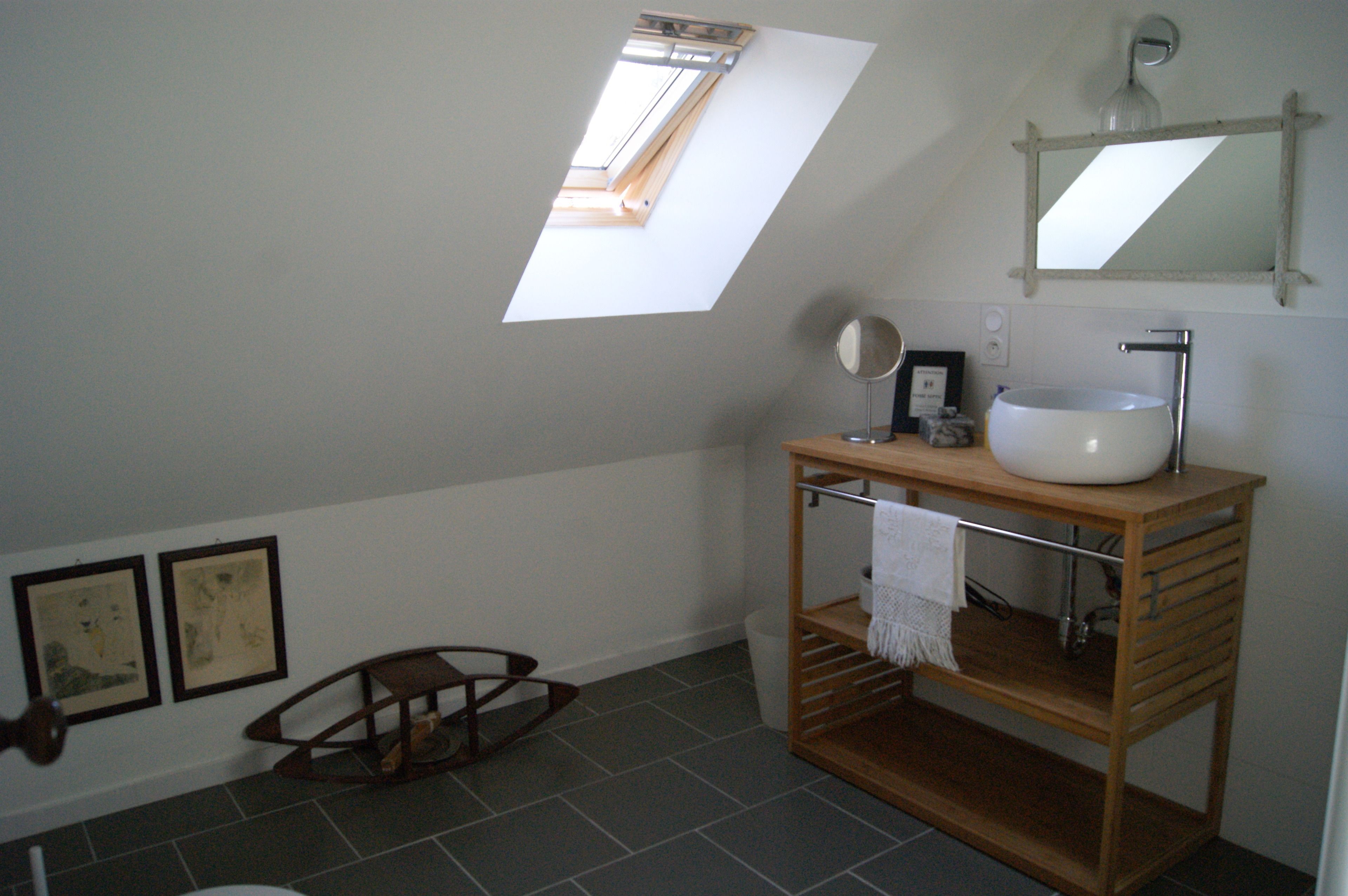 A bathroom with a skylight, a wooden vanity with a sink, and two framed pictures on the wall.
