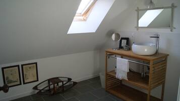 A bathroom with a skylight, a wooden vanity with a sink, and two framed pictures on the wall.