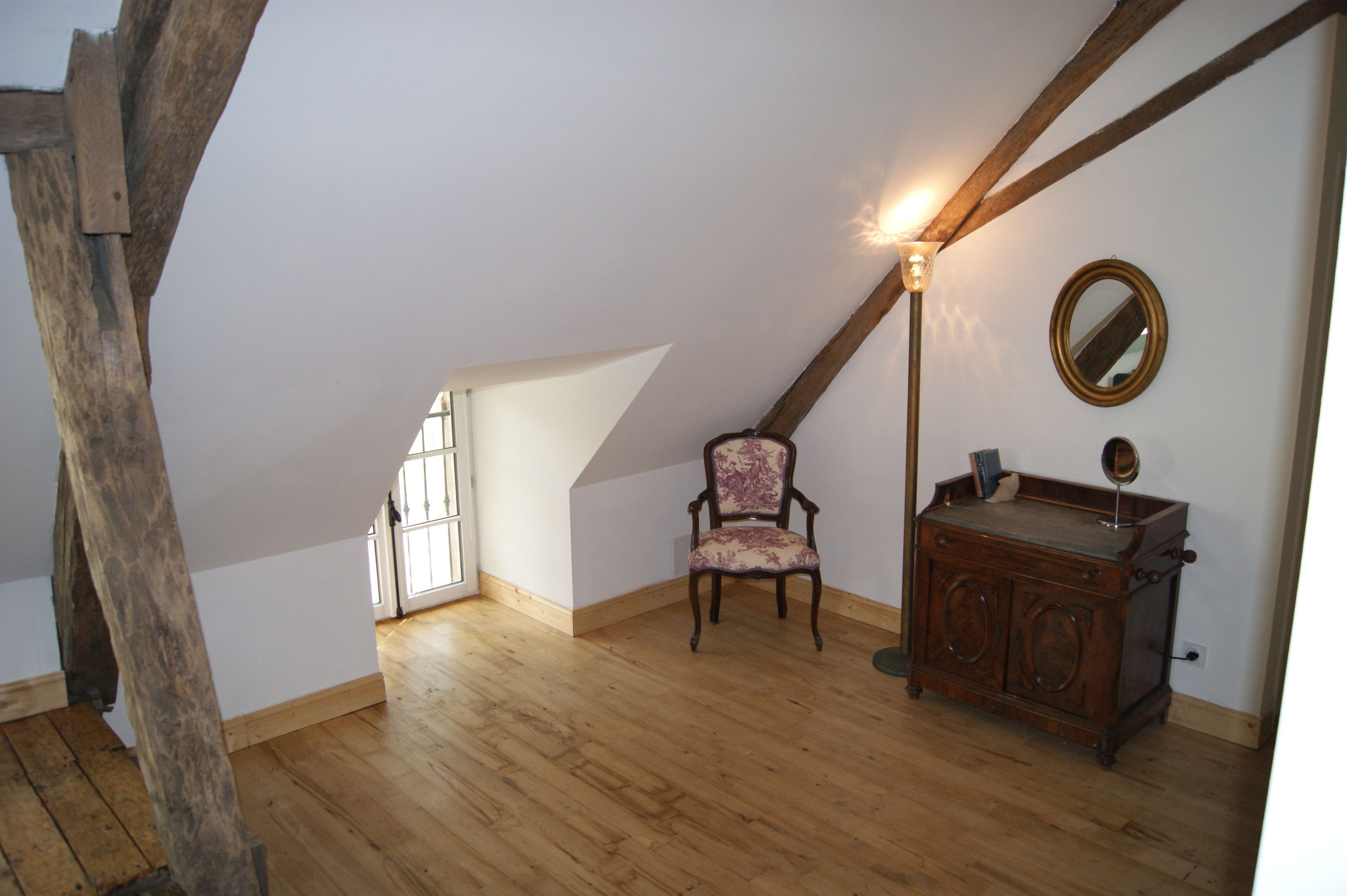 A room with wooden beams, a chair, a dresser, and a mirror.