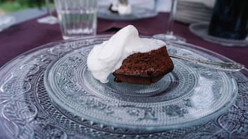 A dessert on a glass plate with intricate patterns, a glass of water, and a wine glass in the background.