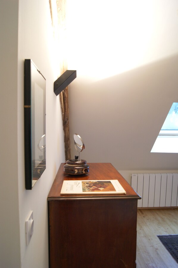 Una habitación con un escritorio de madera, un espejo y un cuadro enmarcado.