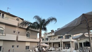A swimming pool with a lifebuoy, lounge chairs, and a palm tree in a resort setting. - Sirena Apartments (Malevizi)