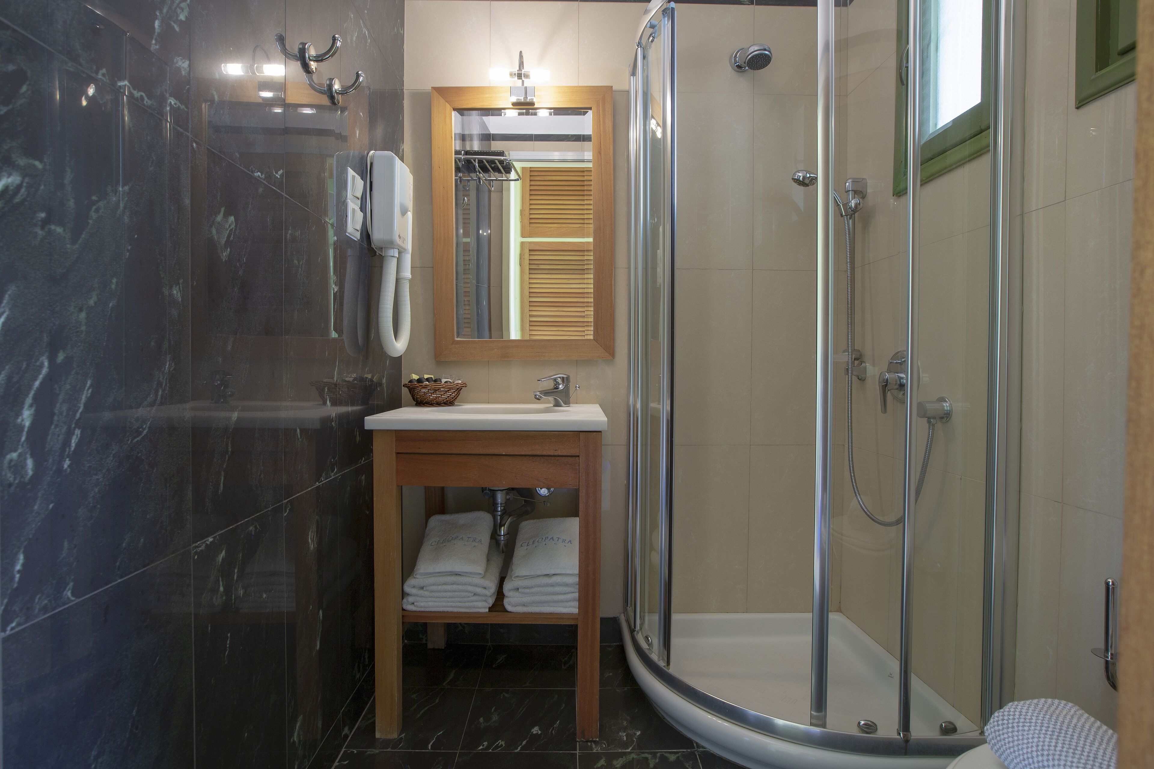 Ein modernes Badezimmer mit einer Duschkabine aus Glas, einem Holzkosmetikschrank mit Waschbecken und einem Spiegel darüber.