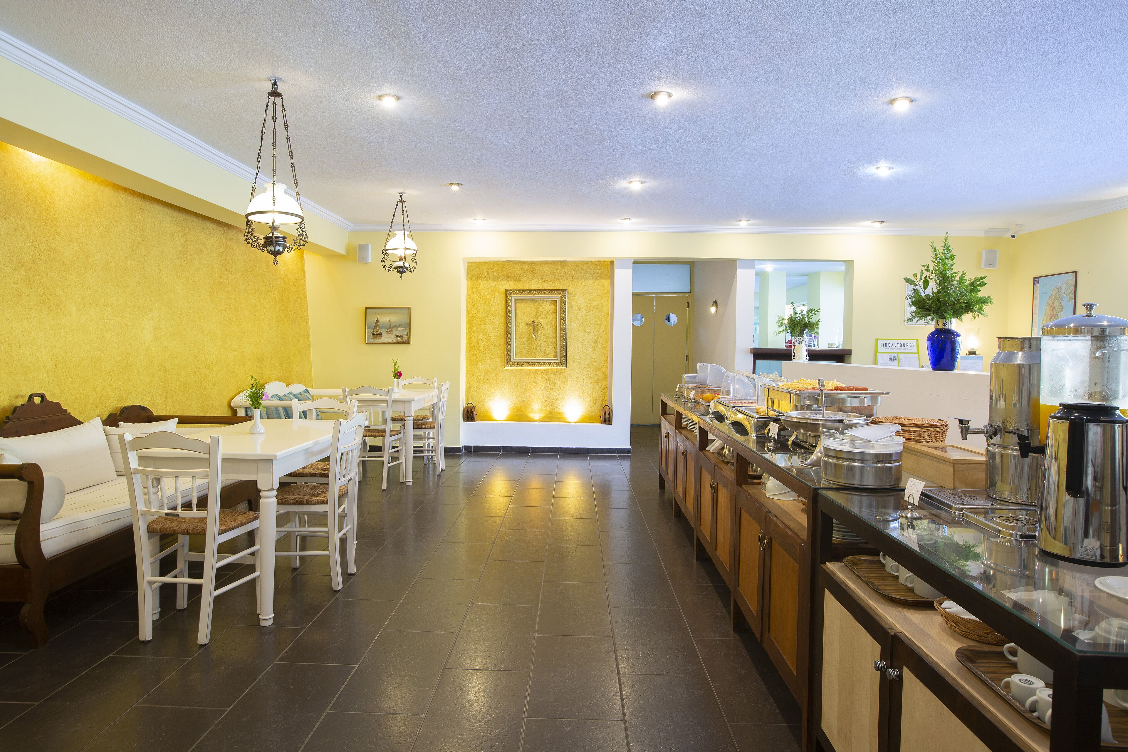 Un comedor de hotel con barra libre, una zona de estar con sofá y sillones, y una mesa de recepción.