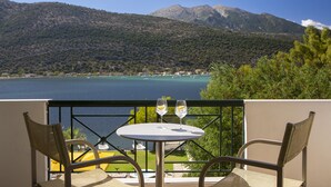 A balcony with a table and two chairs, overlooking a lake with mountains in the background. - Cleopatra Beach Hotel (Lefkada)