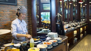 A buffet setup with various dishes and a chef preparing food.