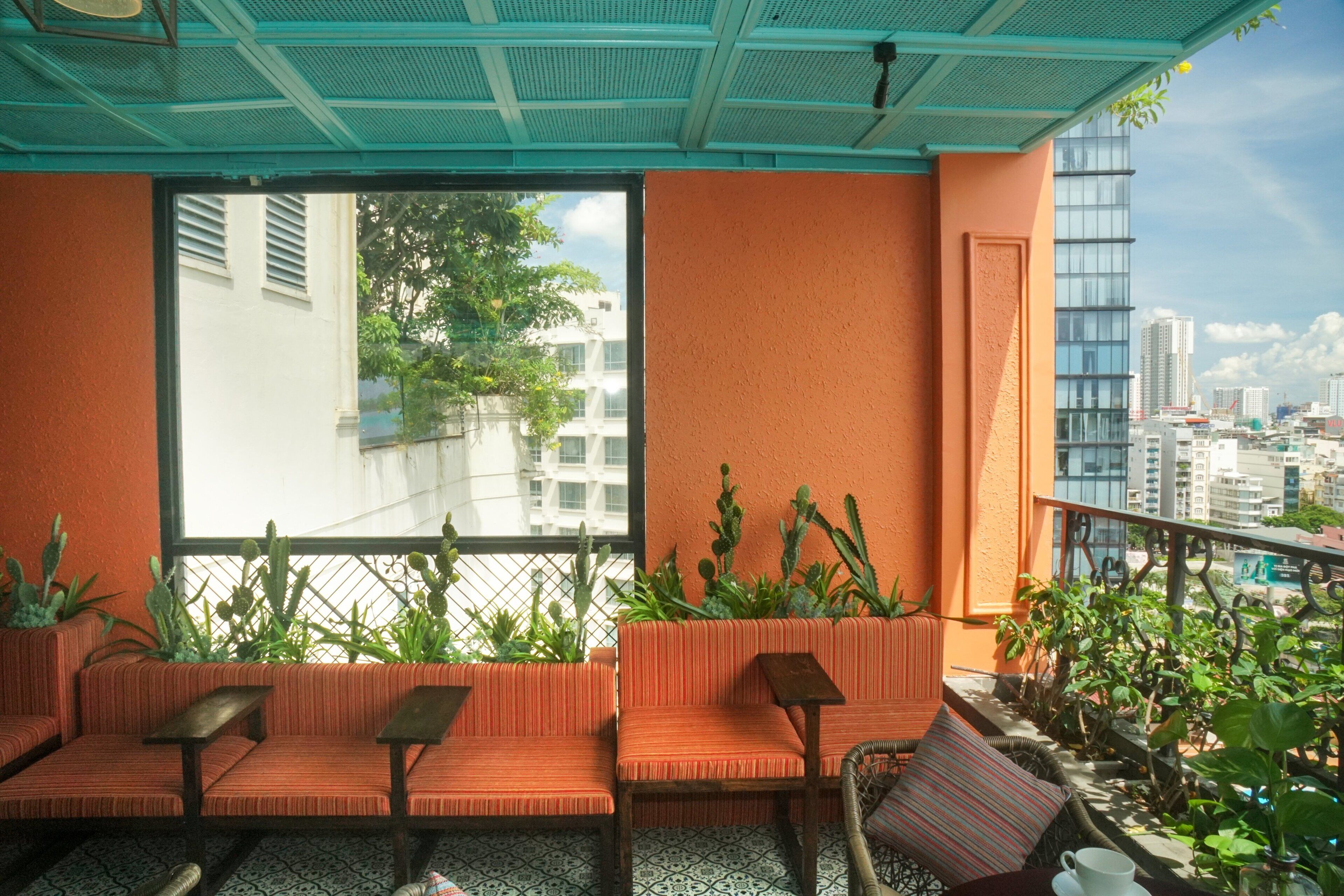 Un balcón con paredes color naranja, vistas de la ciudad y varias plantas.