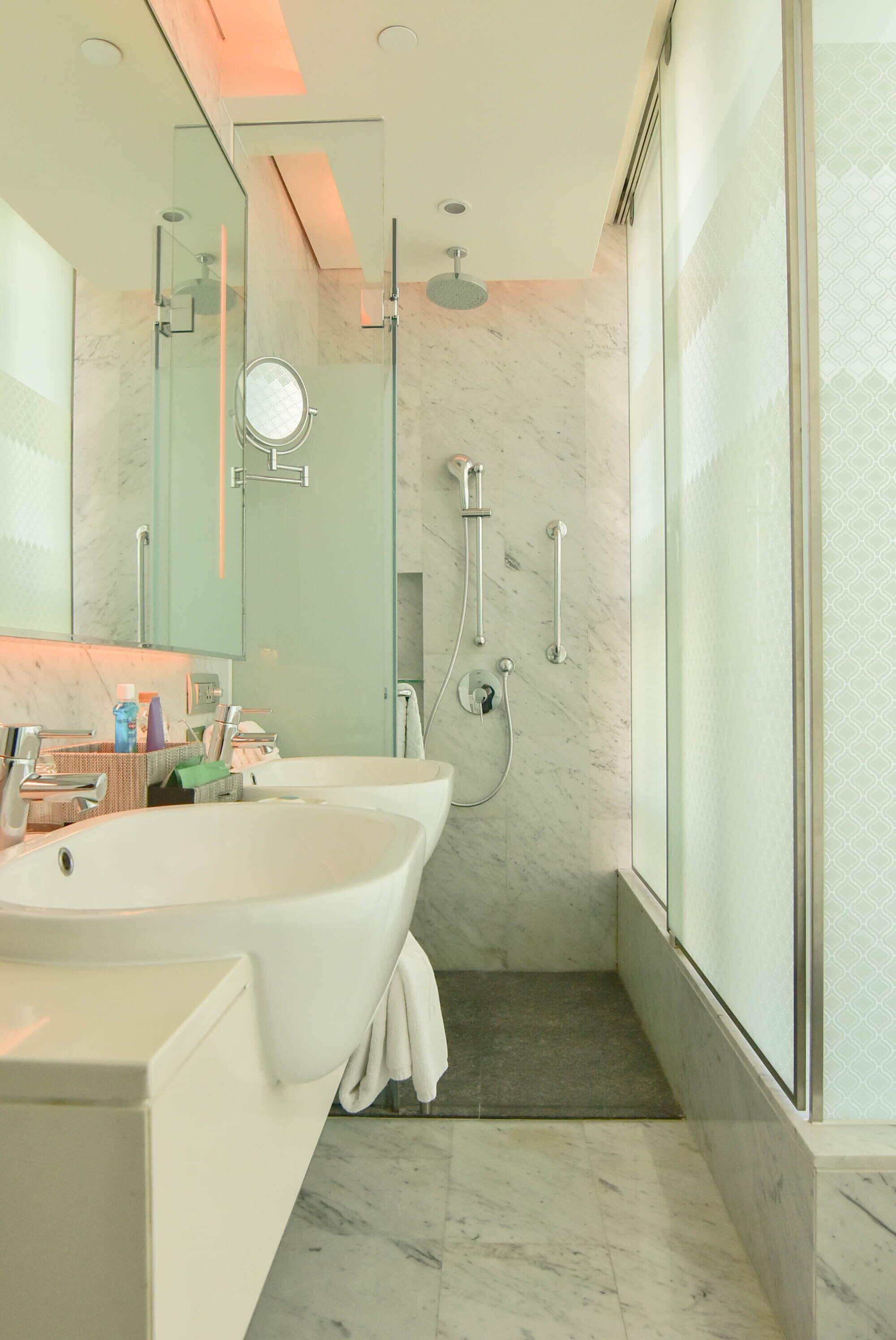 Un baño moderno con una bañera independiente grande, una ducha con cerramiento de vidrio y suelo de mármol.
