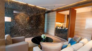 A modern living room with a marble wall, a round coffee table, and a sofa with patterned cushions.