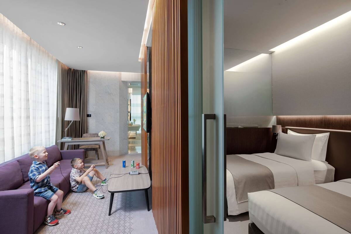 Een hotelkamer met een bank, een kleintje tafeltje, een bed en een televisie.