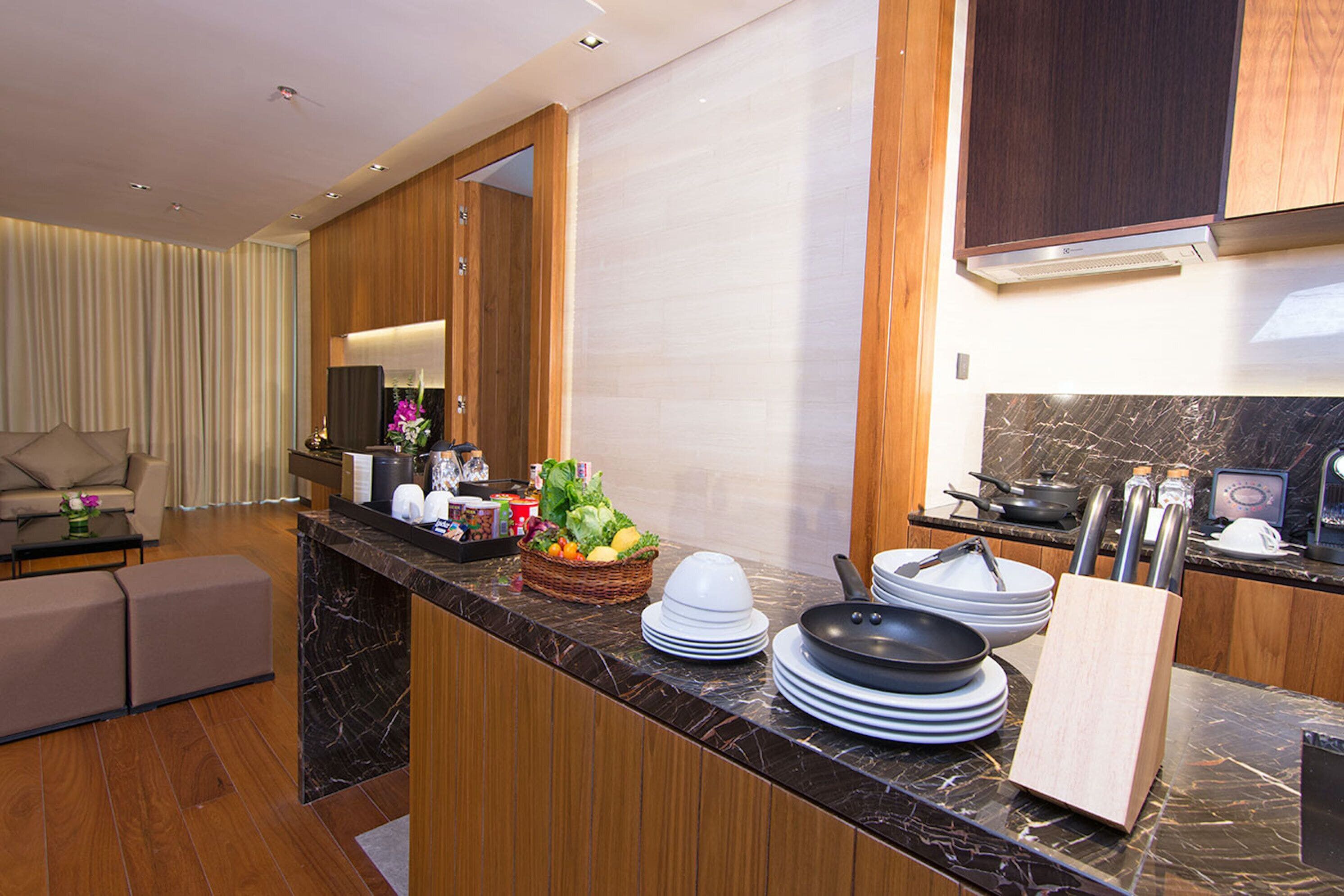 A modern kitchen with a marble countertop, wooden cabinets, and a dining area with a sofa and a coffee table.