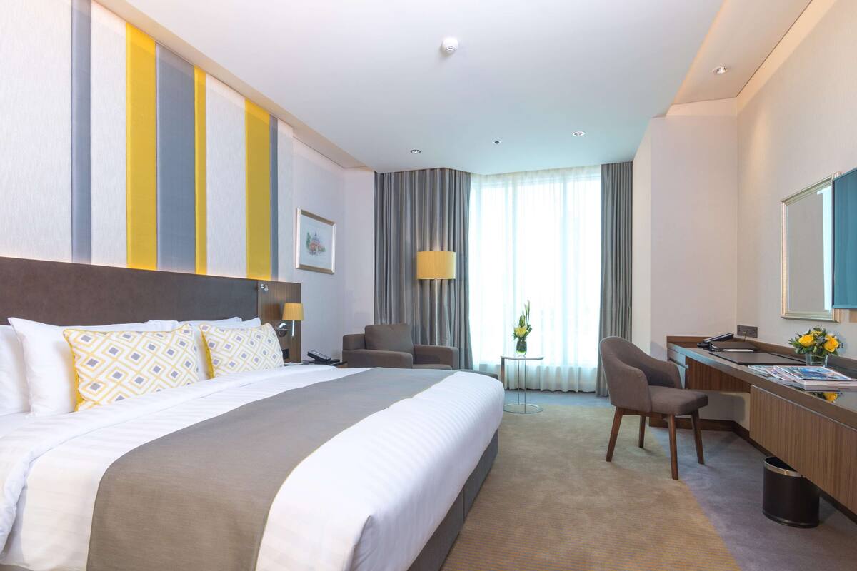 Een hotelkamer met een groot bed, een bureau, een stoel en een televisie.