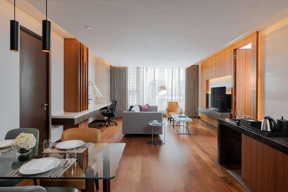 Een moderne hotelkamer met een zithoek, een bank, een televisie en een keukenblad.