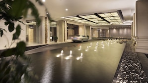 Un moderno vestíbulo de hotel con piso reflectante, un coche en movimiento y un amplio tragaluz.