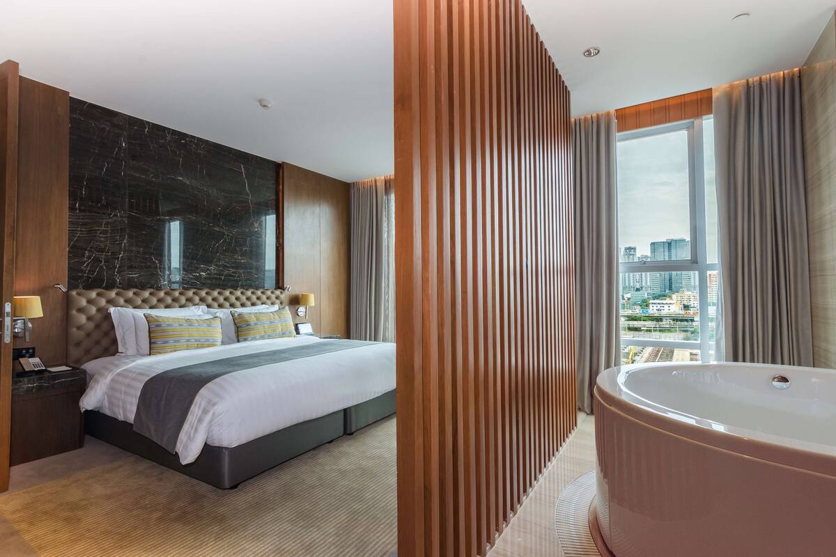 Een moderne hotelkamer met een groot bed, een inbouwbad en uitzicht op de stad.