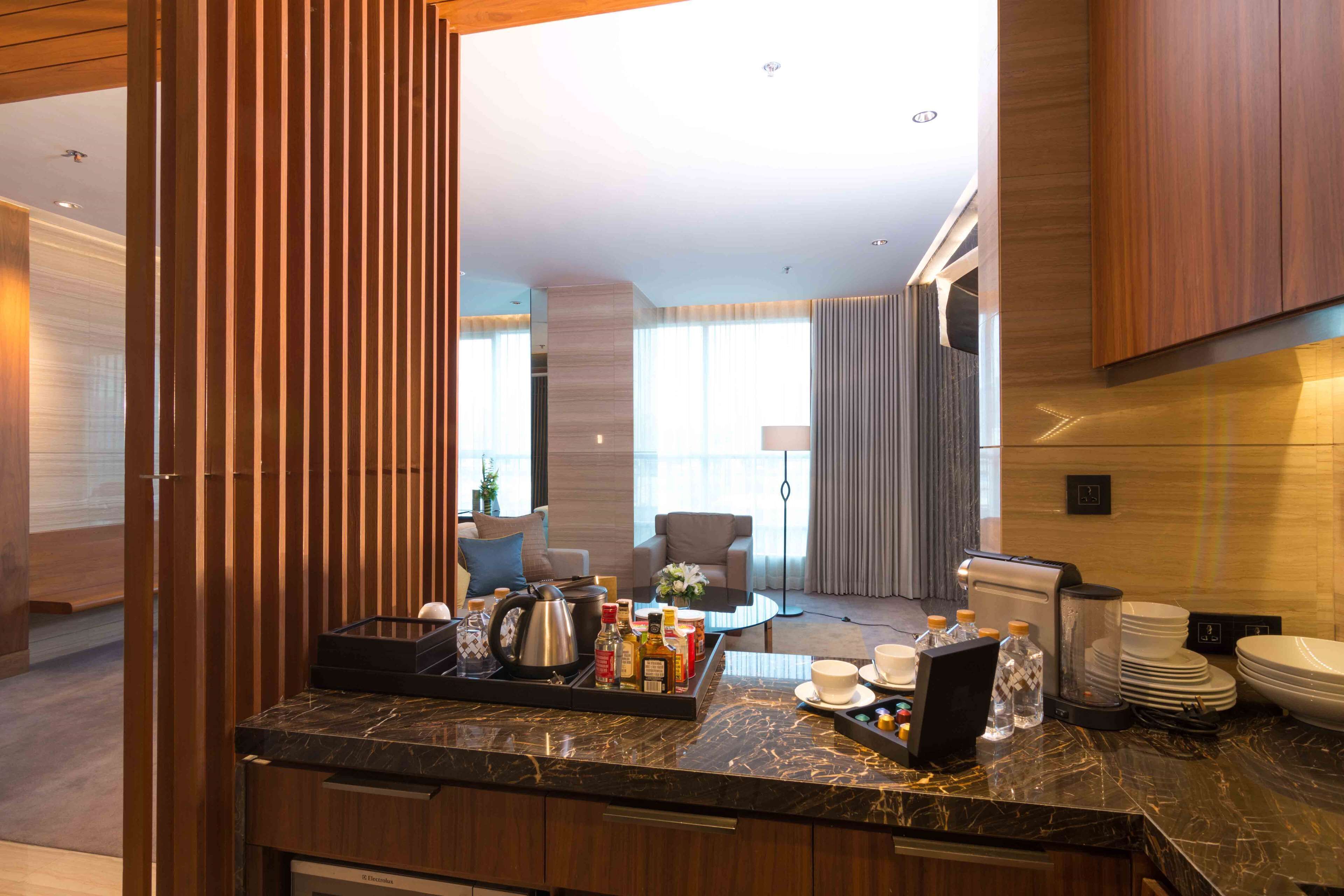 A modern hotel kitchen with a marble countertop, a coffee maker, and a tray with condiments.