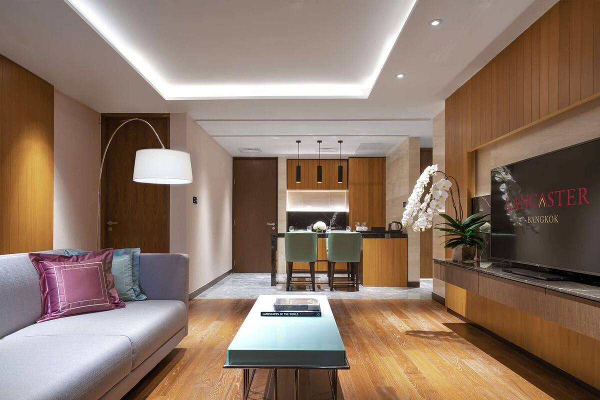 Een moderne woonkamer met een bank, salontafel en een televisie aan een houten wand.