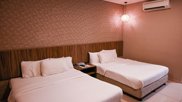 A hotel room with two beds, a wooden headboard, an air conditioning unit, and a nightstand with a lamp. - Hotel Jelai Raub (Raub)