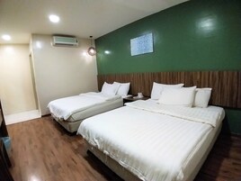 Habitación de hotel con dos camas, una mesita de noche, aire acondicionado de pared y lámpara colgante.