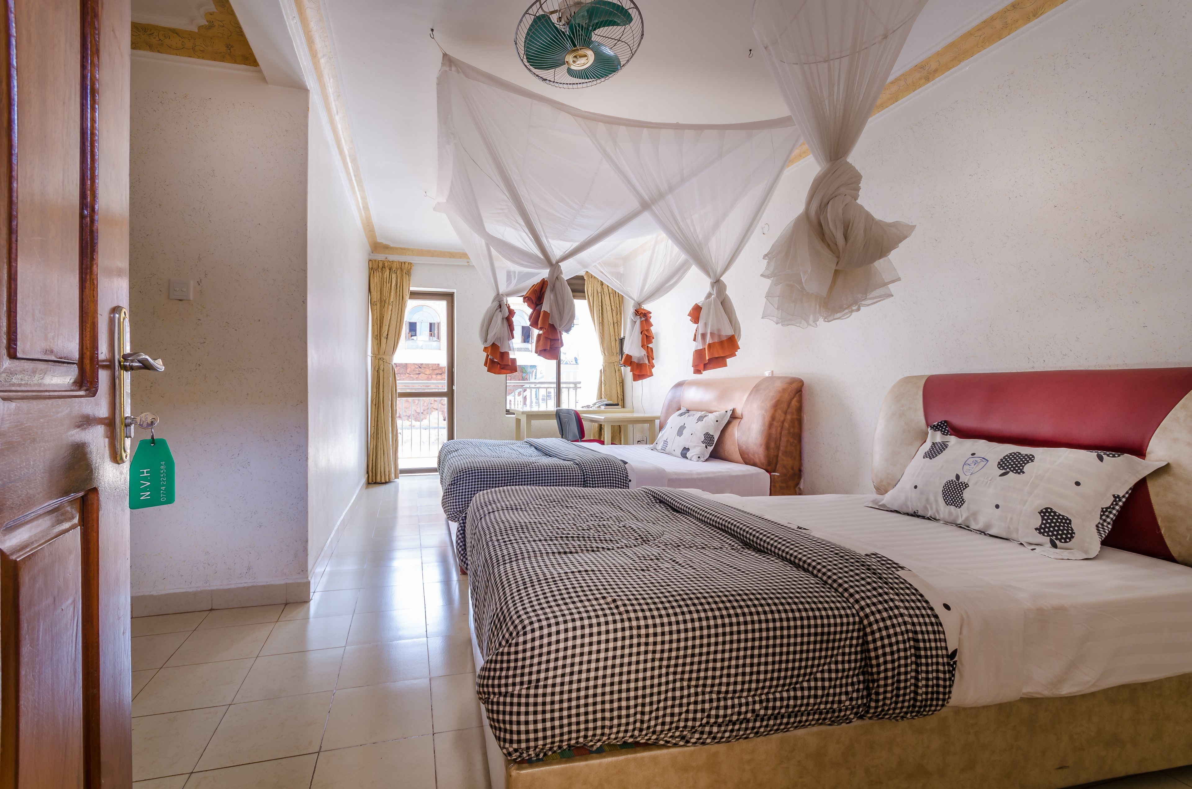 Una habitación de hotel con cama, una silla, un escritorio y ventana con cortinas.