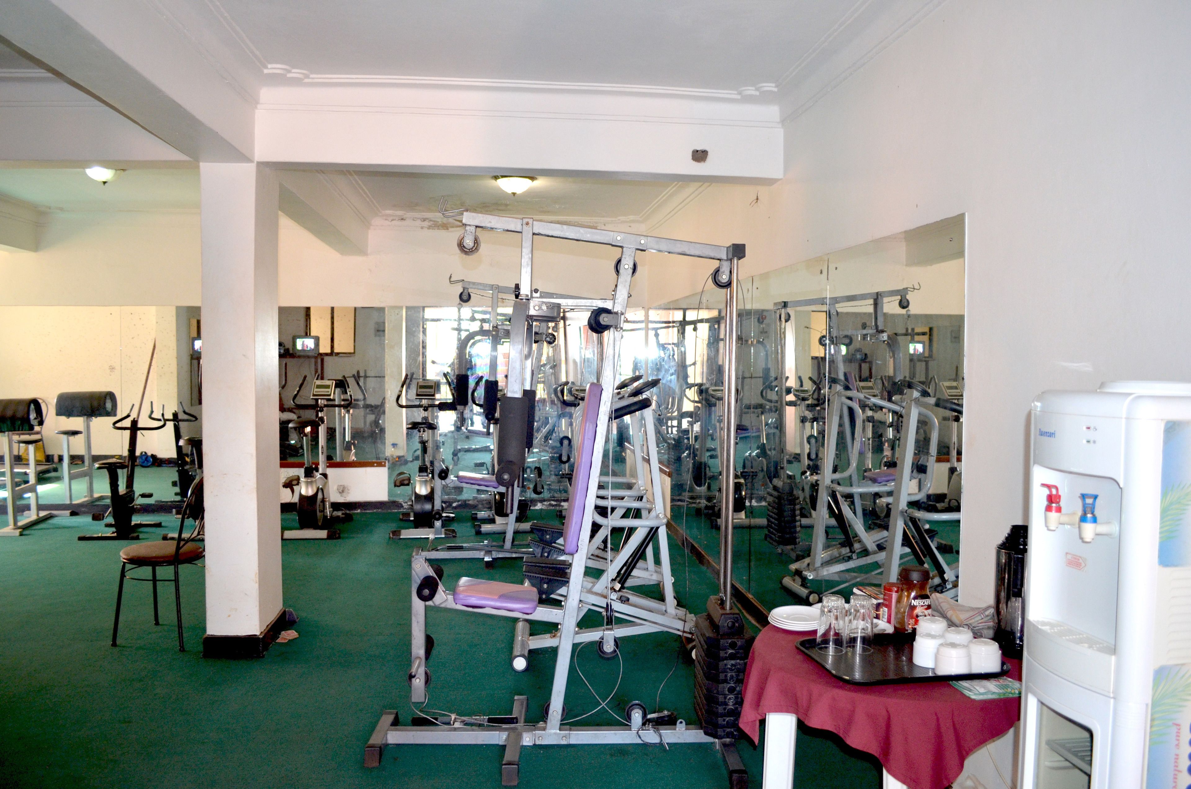 A gym with various exercise equipment, a water dispenser, and a mirror.