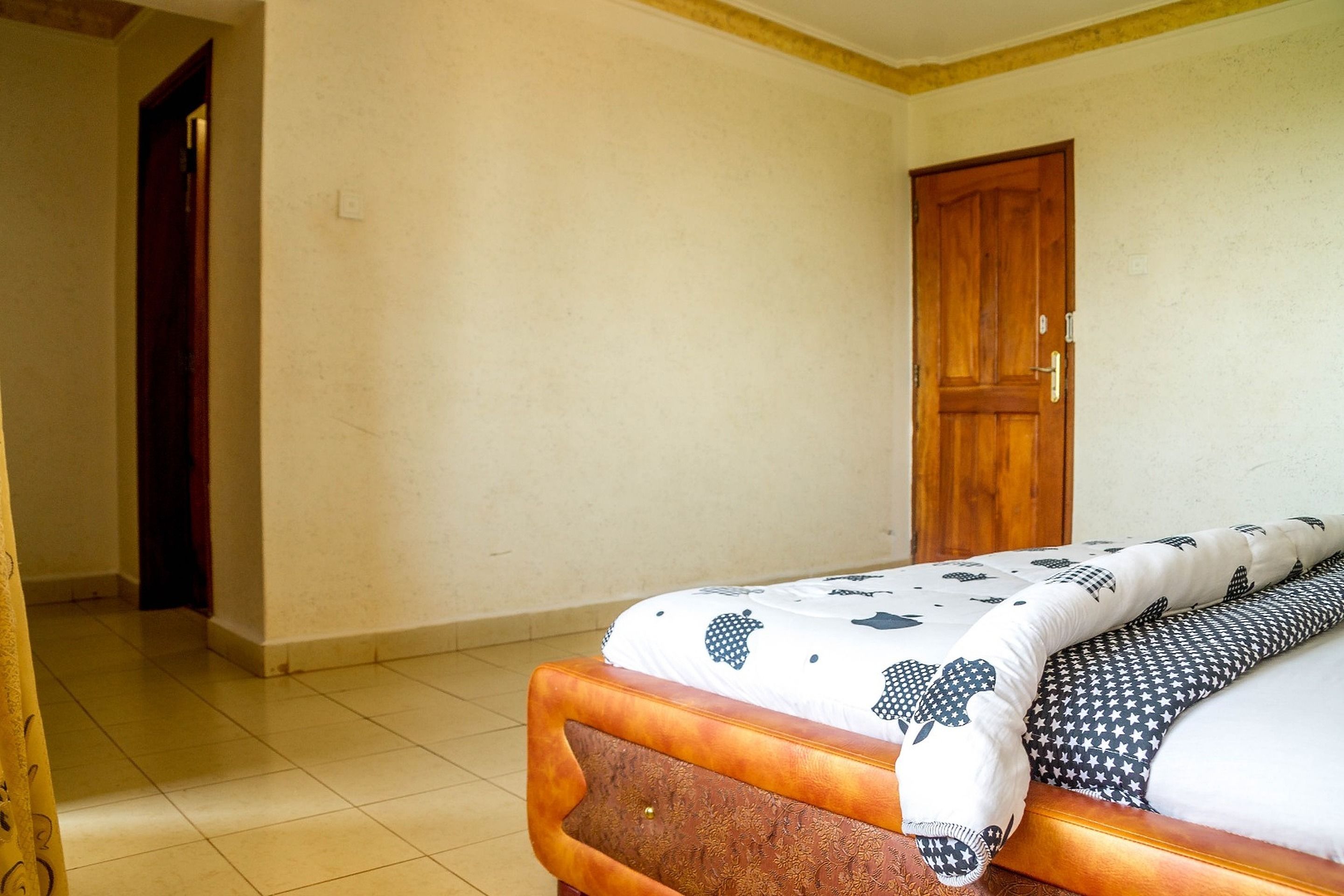A bedroom with a bed, a wooden door, and a tiled floor.