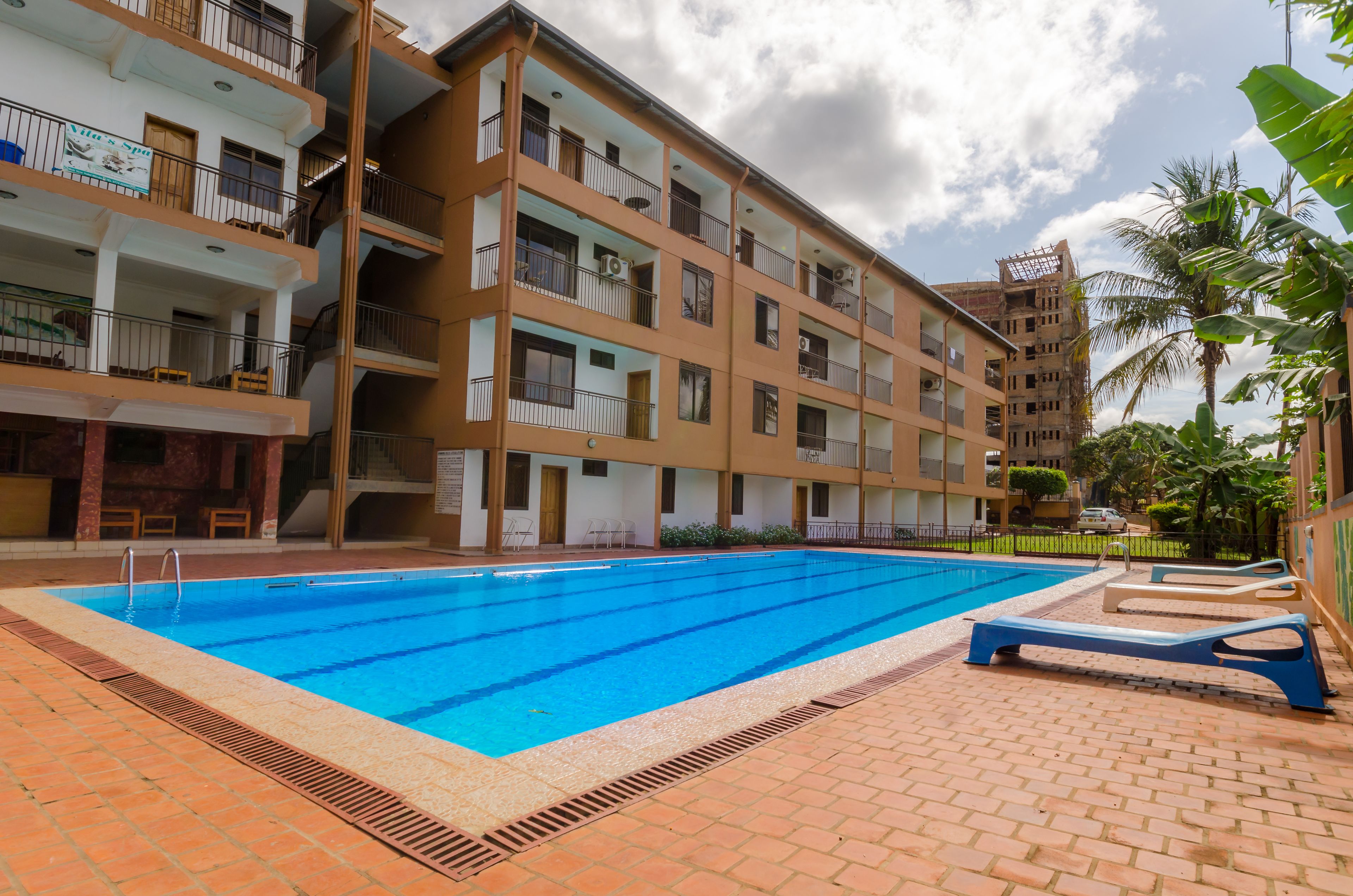 A multi-story building with a swimming pool, outdoor seating, and a well-maintained garden.