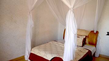 A single bed with a canopy, a bedside table, and a wall socket.