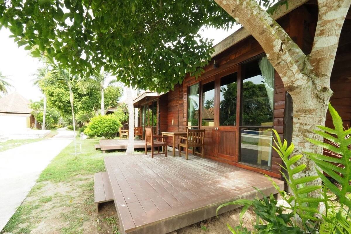 A wooden cabin with a porch, outdoor seating, and a view of the surrounding greenery.