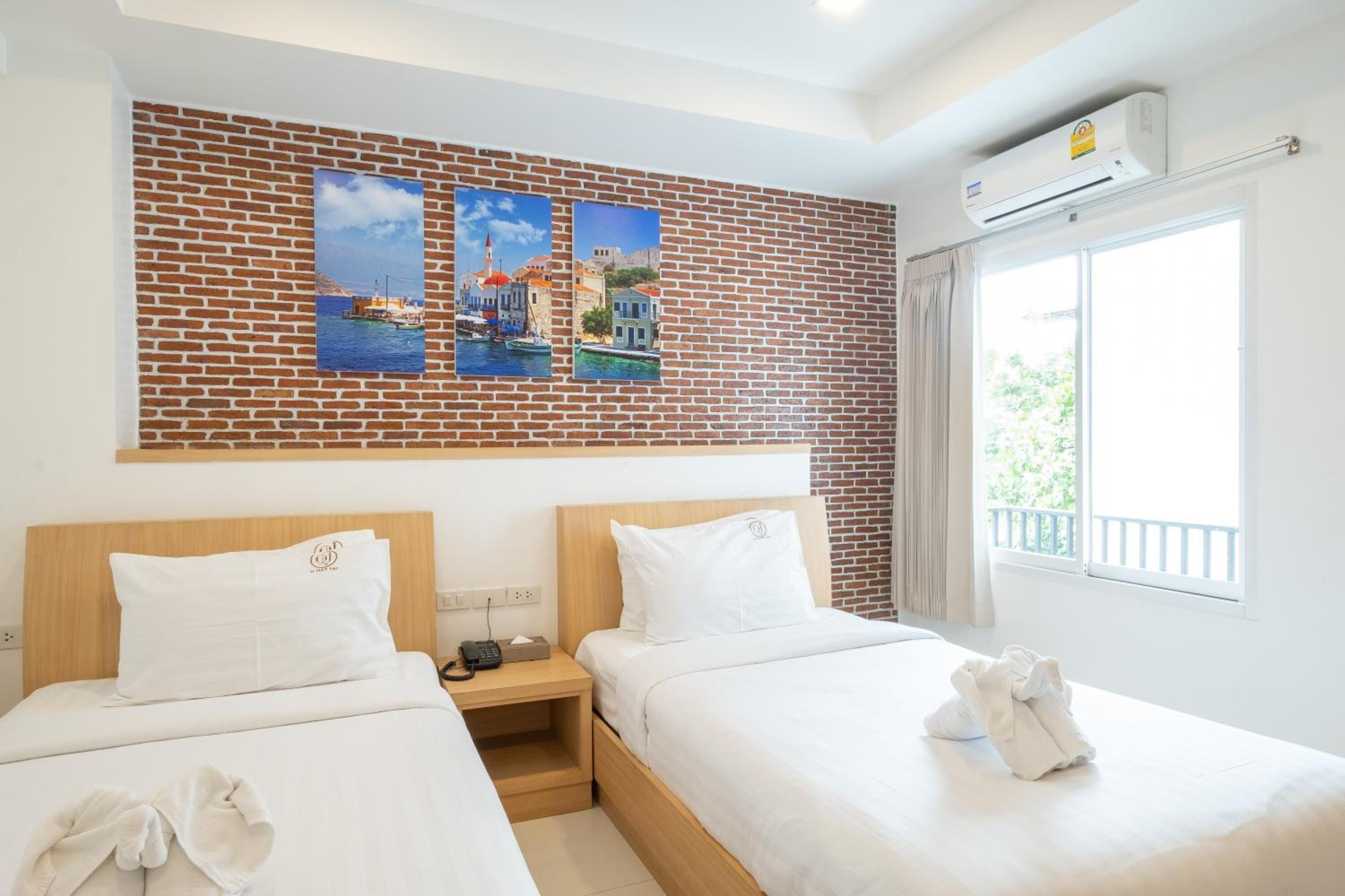 Une chambre d’hôtel avec deux lits, un mur en briques et une fenêtre donnant sur un paysage agréable.