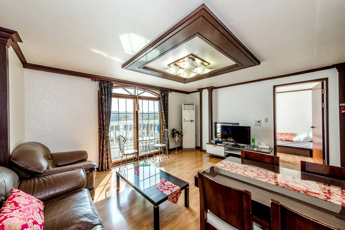 Un salon avec un canapé, une table basse, un téléviseur et un balcon offrant une vue agréable.
