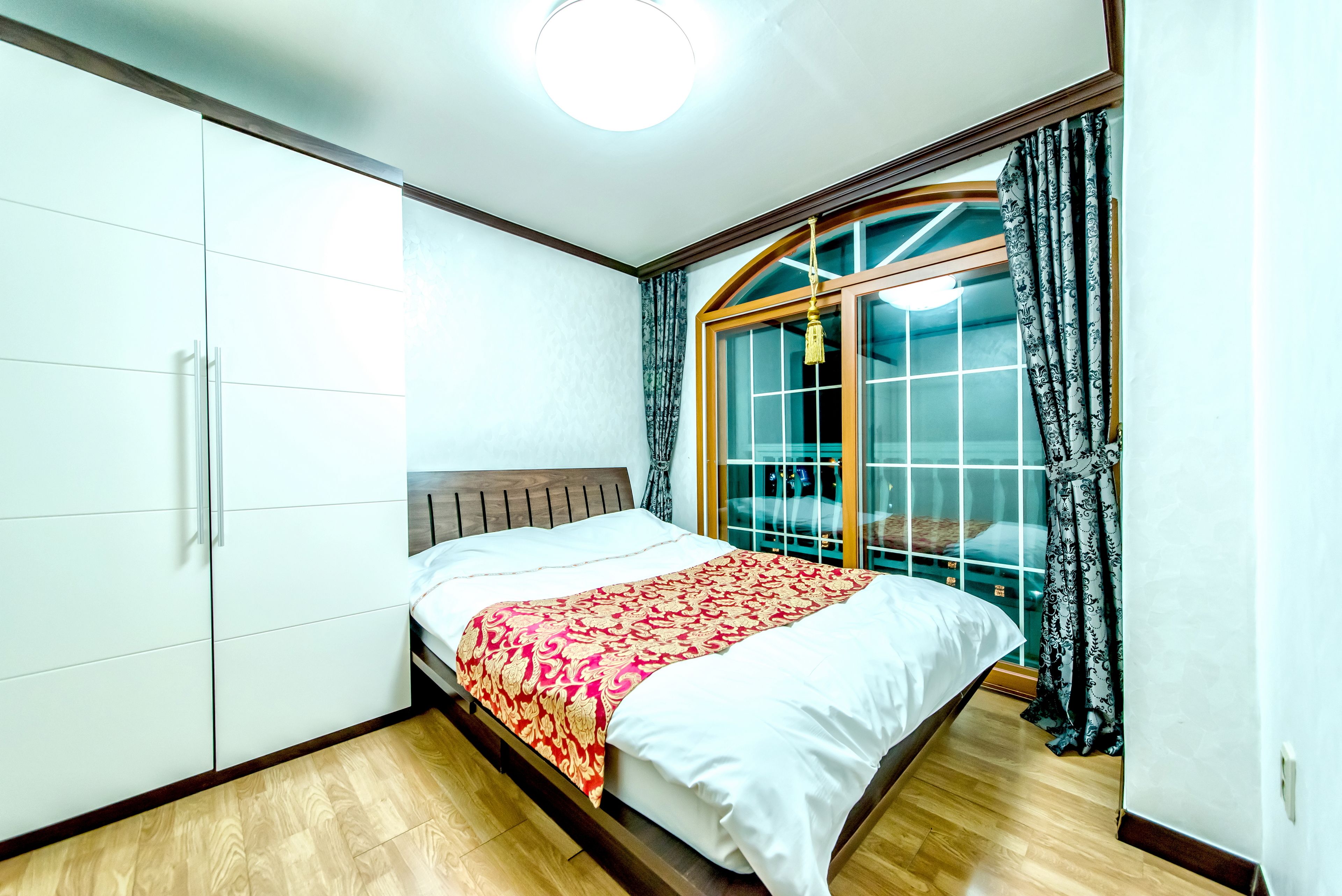 A bedroom with a bed, wardrobe, and a sliding glass door to a balcony.