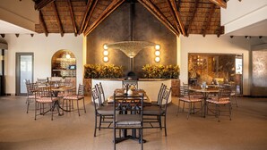 Uma sala de jantar com teto alto, um lustre central e lareira.