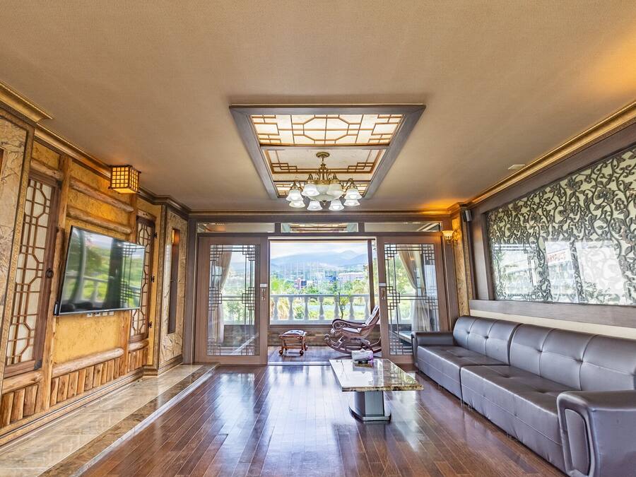 A spacious living area with a sofa, a coffee table, and a TV mounted on the wall.