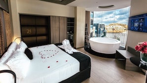Ein modernes Hotelzimmer mit einem großen Bett, einer Badewanne und Blick auf die Stadt.