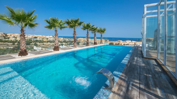 Ein Swimmingpool mit Palmen und Blick auf das Meer.