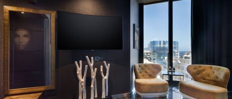 Una sala de estar moderna con un televisor de pantalla plana grande, un sofá y una pieza escultórica original.