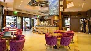 Eine Hotelhalle mit mehreren Sitzbereichen, einer Bar und sichtbaren Toiletten.