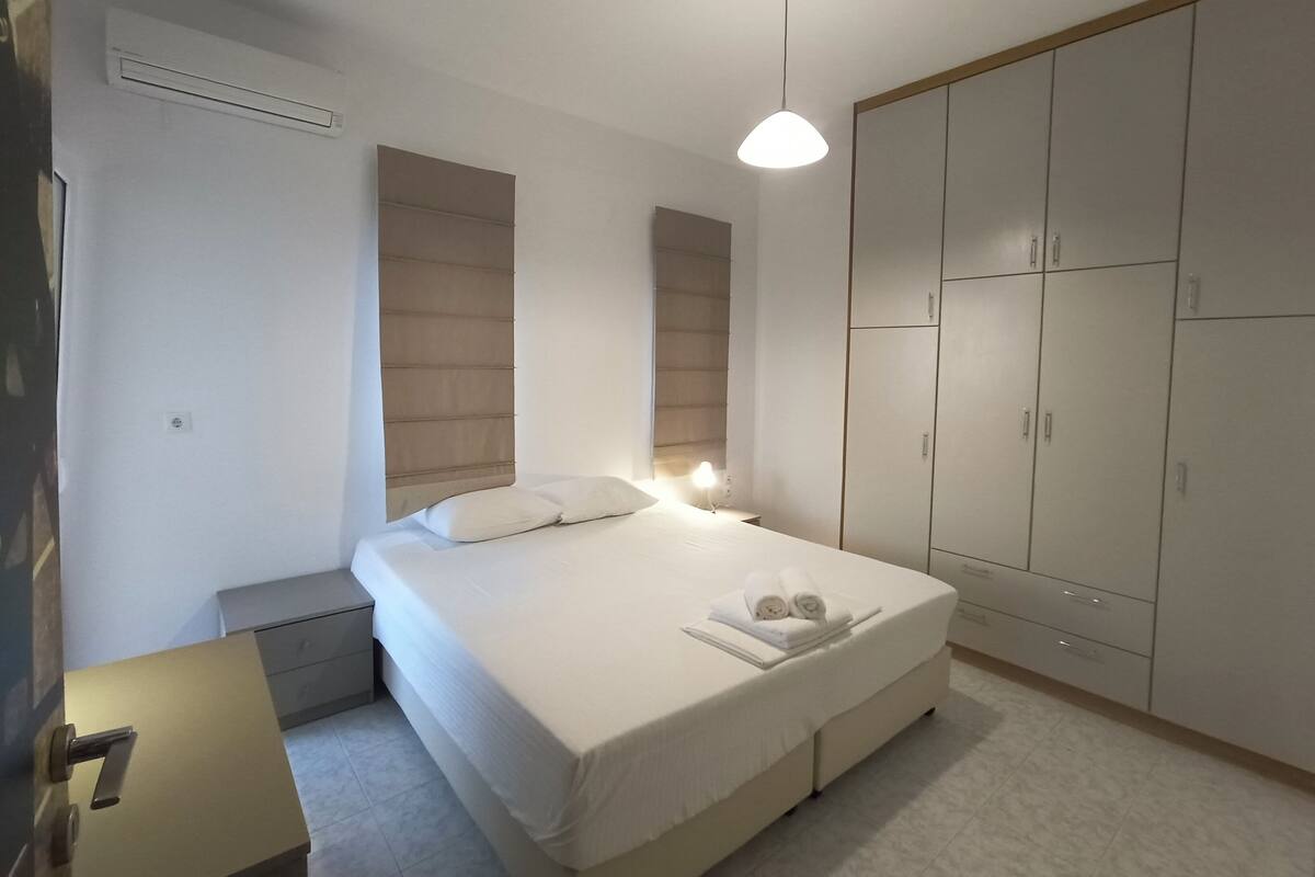 A bedroom with a bed, bedside tables, a wardrobe, and a hanging light fixture.