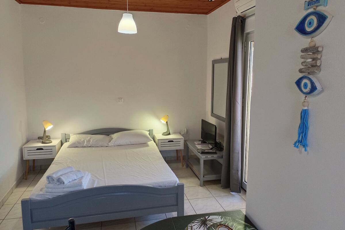 A bedroom with a bed, bedside lamps, a TV, and a wall decoration.